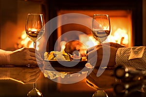 Young couple have romantic dinner with wine over fireplace background.