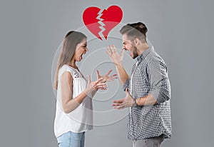 Young couple having argument and illustration of broken heart on grey background. Relationship problems