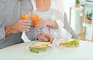 Young couple having breakfast with sandwiches at table in kitchen