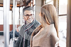 Young couple having a conversation while sitting inside vintage tram transport - Happy people talking during a journey in bus
