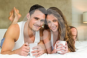 Young couple having cup of coffee on bed