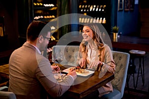 Young couple having a dinner in the restaurant and drinking red wine