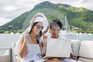 Young couple having fun on the boat with a laptop.