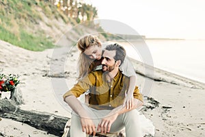 A young couple is having fun and hugging on the beach. Beautiful girl embrace her boyfriend from back. Wedding walk. A