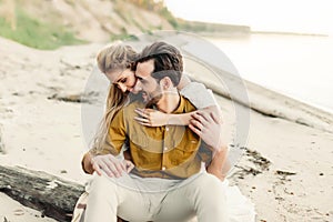 A young couple is having fun and hugging on the beach. Beautiful girl embrace her boyfriend from back. Wedding walk. A