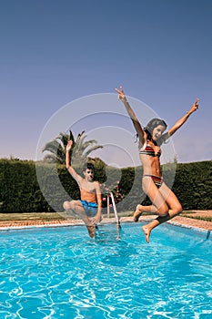 Young couple having fun jumping in the pool