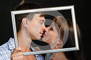 Young couple having fun making faces through frame