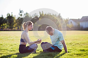 Young couple having fun outdoors together on field with green grass at sunrise