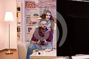 Young couple having fun while playing video games on televison