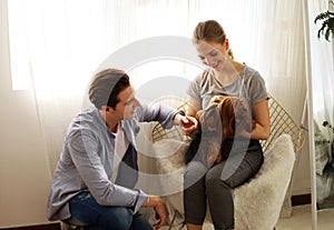 Young couple having fun with their favorite dog at home.