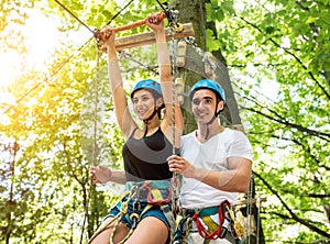 Young couple having fun time in adventure rope park.