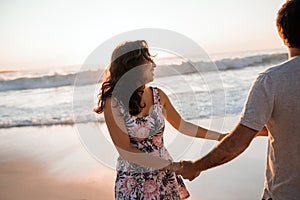 Young couple having fun together on a beach at sunset