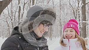 Young couple having fun together in snow in winter woodland throwing snowballs