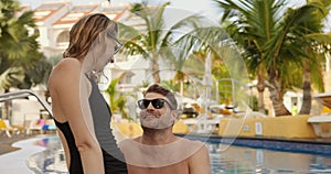 young couple having fun together by tropical resort hotel swimming pool. summer vacation, romantic getaway