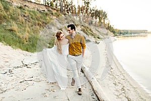 A young couple is having fun and walking on the sea coastline. Newlyweds looking at each other with tenderness. Romantic