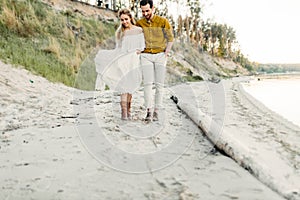 A young couple is having fun and walking on the sea coastline. Newlyweds looking at each other with tenderness. Romantic