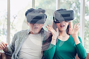 Young Couple Having Fun While Watching Video Via Virtual Reality Together. Couple Love Having Enjoyment With Electronic VR Goggles