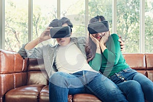 Young Couple Having Fun While Watching Video Via Virtual Reality Together. Couple Love Having Enjoyment With Electronic VR Goggles