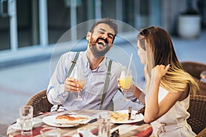 Young couple having good time in cafe restaurant. They are smiling and eating a pizza