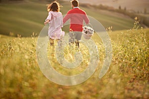 A young couple having a good time while running over a large meadow. Love, relationship, together, nature
