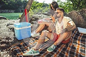 Young couple having picnic at riverside in sunny day