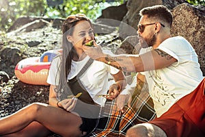 Young couple having picnic at riverside in sunny day