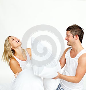 Young couple having a pillow fight with copy-space