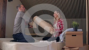 Young couple having a pillow fight in a home bedroom