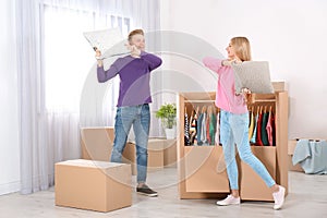 Young couple having pillow fight near wardrobe boxes