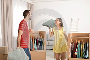Young couple having pillow fight near wardrobe boxes