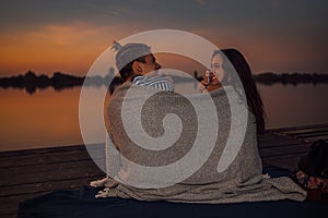 Young couple having a romantic date by the river, covered with blanket
