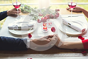 Young couple having romantic dinner in the restaurant sitting holding hands close-up