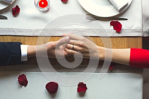 Young couple having romantic dinner in the restaurant wearing a proposal ring top view
