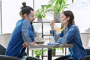 Young couple having serious conversation while sitting together in cafe