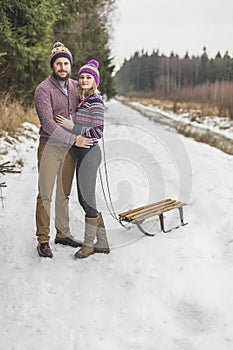 Young couple having a sled winter forest walk