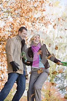 Young couple having throwing leaves in the air