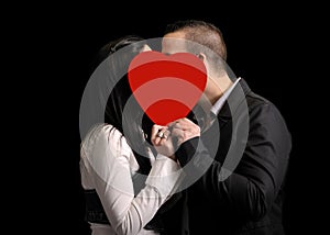 Young couple hiding behind a red heartshape
