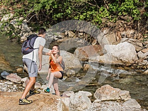 Young couple hiking along a mountain river shore