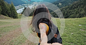 Young couple hiking and enjoying a mountains view. Woman follow me laughing and smiling on beautiful Alpine landscape