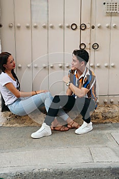 A young couple of hipsters in love, dressed casually, sitting on the floor, happy, having fun