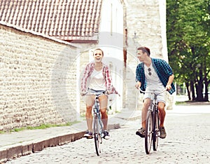 Young couple of hipsters riding a bicycle. Date in old town. Love, relationship, romance concept.