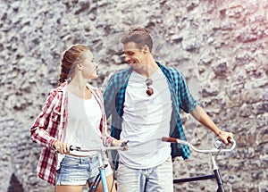 Young couple of hipsters riding a bicycle. Date in old town. Love, relationship, romance concept.