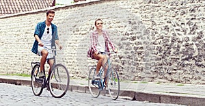Young couple of hipsters riding a bicycle. Date in old town. Love, relationship, romance concept.
