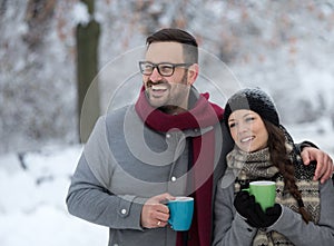 Man and woman with hot drink on snow