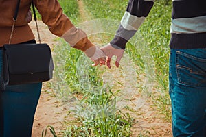 Young couple holding hands on the background of green grass