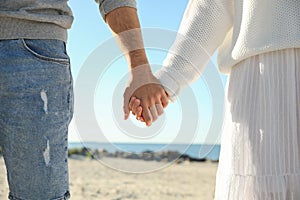 Young couple holding hands on beach. Honeymoon trip