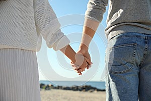 Young couple holding hands on beach. Honeymoon trip