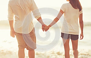 Young Couple Holding Hands on the Beach at Sunset photo