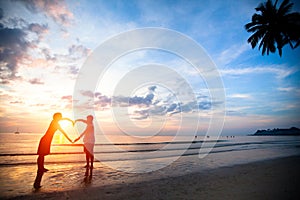 Young couple holding hands heart-shaped on the sea beach