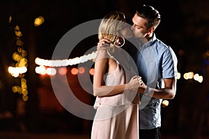 young couple holding hands and kissing on river beach